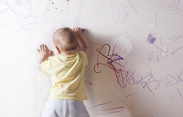 Baby boy drawing on plasterboard wall