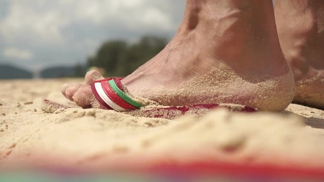 Man Putting Feet In Sandals On The Beach And Go To The Sea, Closeup, Big Closeup