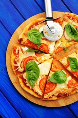 Cutted margherita pizza with round knife and basil