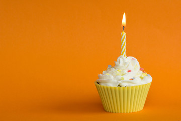 yellow cupcake with candle and orange background