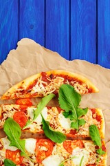 Rucola pizza on wrinkled craft paper with blue background