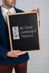 Man in a suit with a black board in his hands on a white backgro