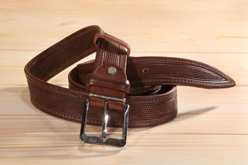 Leather belt with metal buckle on wooden background