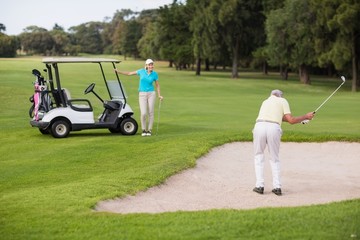 Obraz premium Mature golfer standing on sand trap by woman 