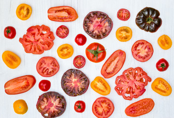 Different  types and colors of tomato slices on a white board