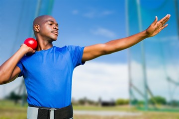 Composite image of front view of sportsman practising shot put 