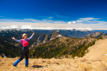 Naklejka premium Kobieta latem górski dzień. Trasa kamienista. Niebieskie niebo. Śnieg i