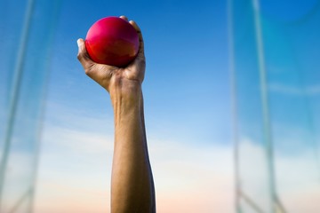 Composite image of hand holding a red ball