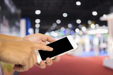 Hand hold smartphone on blur exhibition background