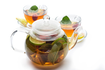 Fruit tea with mint leaves in a teapot on a white background