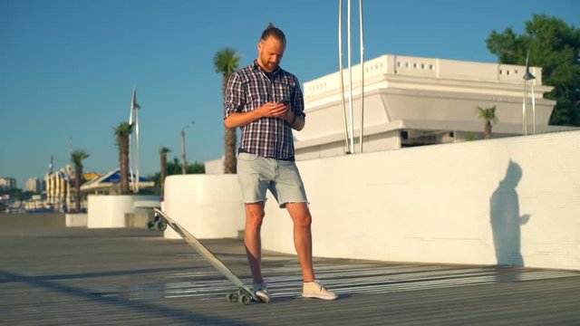 handsome male skateboarder taking picture by smartphone slow motion