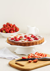 Homemade strawberry cake on a white cake stand.