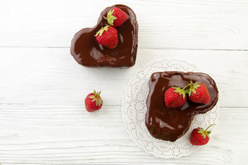 Heart cake. Pieces of chocolate cake with fresh strawberry on wooden background. Top view.