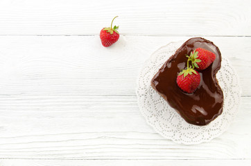 Heart cake. Chocolate cake with fresh strawberry on wooden background. Top view.