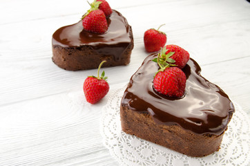 Heart cake. Pieces of chocolate cake with fresh strawberry on wooden background. Top view.