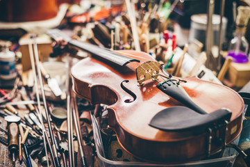 Close up of violin, luthier workshop in background