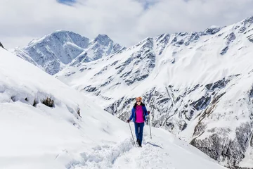 Fotobehang Hiker happy woman trekking on the snow in a snowy Caucasus mountains at spring © EdNurg