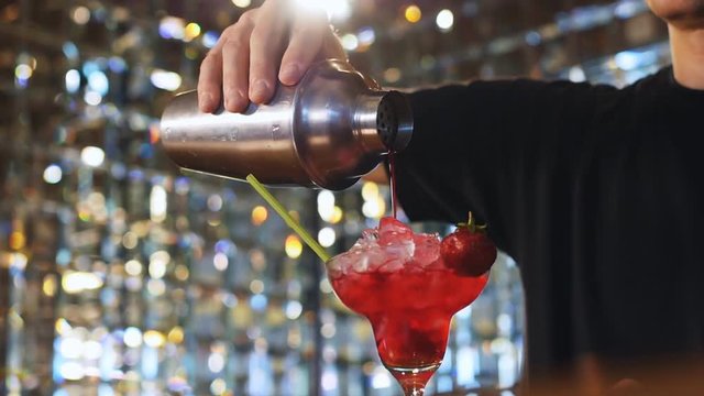 The barman prepares alcoholic cocktail with strawberry