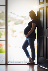 Happy Chinese Pregnant Woman Standing Silhouetted in Doorway.