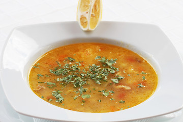 Chicken soup with noodles and vegetables in white bowl