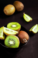 Kiwi slices in a bowl on a black stone table