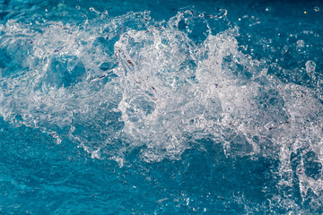 Water splash in swimming pool with blue floor. Fresh background