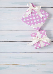 Gift wrap - Presents wrapped in pink wrapping paper with white silk ribbon bows and on a rustic painted wooden table top background forming a page border