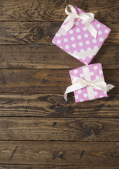 Gift wrap - Presents wrapped in pink wrapping paper with white silk ribbon bows on a rustic wooden table top background forming a page border