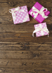 Gift wrap - Presents wrapped in pink wrapping paper with white silk ribbon bows on a rustic wooden table top background forming a page border
