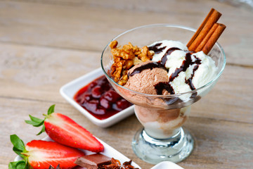 Ice cream sundae, chocolate, walnuts, sliced strawberry and cherry jam