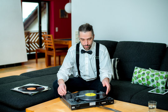 man in white shirt with bow-tie with old records in his living r