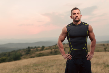 Athletic man in his 30s resting with his hands on his hips while jogging outdoor