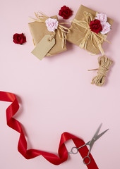 flowers on a pink background with red silk ribbon, string and scissors forming a page border