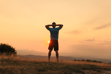 Silhouette of an athletic man in nature in front of a sunset while exercising