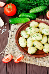 
lunch or dinner , boiled potatoes with dill and fresh vegetables , cucumbers, tomatoes and spices on wooden background