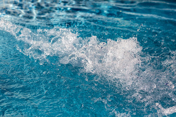 Obraz na płótnie Canvas Close-up of a inflowing water jet into a swimming pool with blue floor