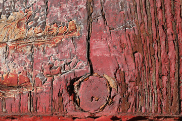 Red cracked paint on an old board, door hinge in the form of arr - obrazy, fototapety, plakaty