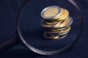 Euro money. Coins are isolated on a dark background. Currency of Europe. Balance of money. Building from coins. View through a magnifier.