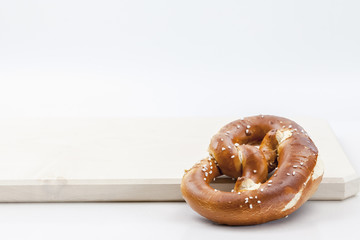 Eine Brezen liegt auf einem Holzbrett, wo ist die Weißwurst?  