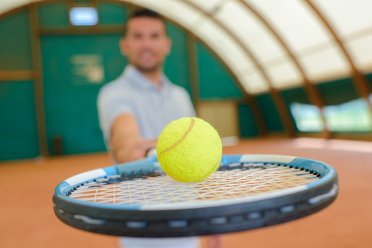 Man holding forward a tennis ball on a racket