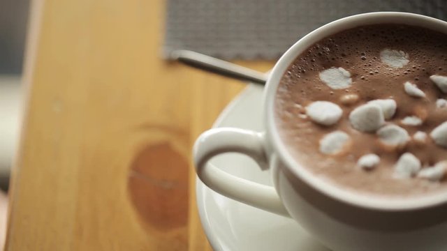 Ceramic cup of hot brown cacao stands on wooden table