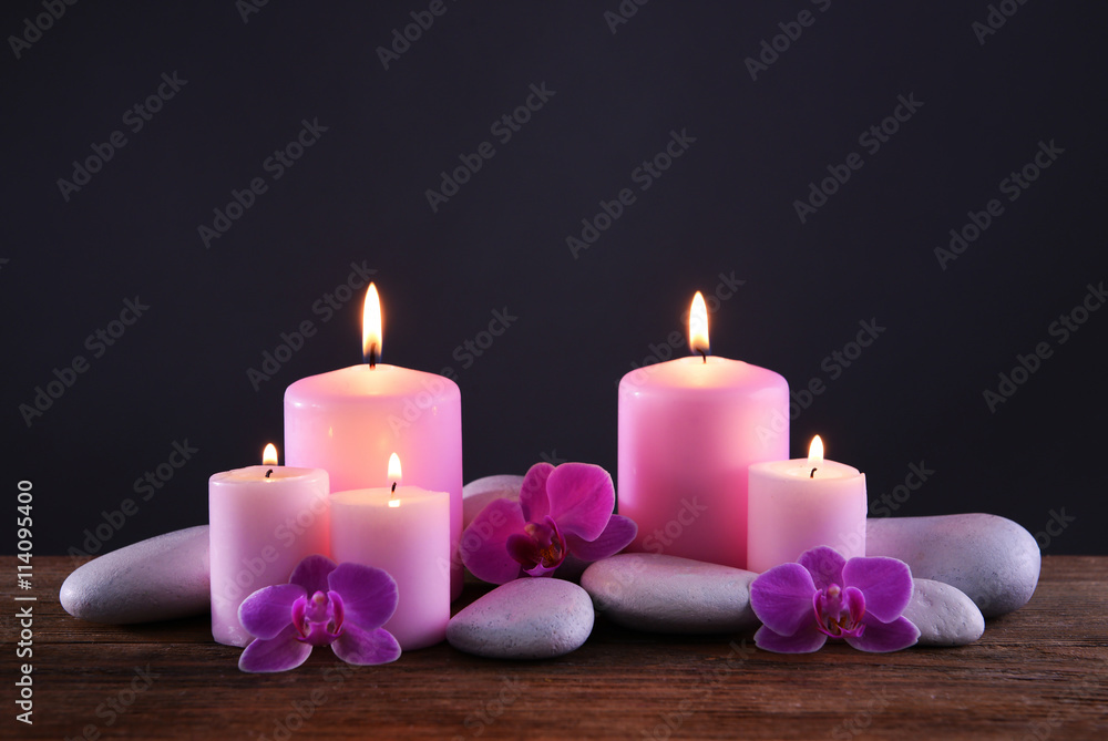 Wall mural Spa stones with burning candles and flowers on grey background