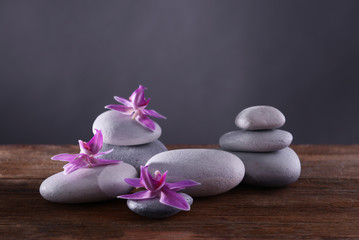 Fototapeta na wymiar Spa stones and flowers on grey background