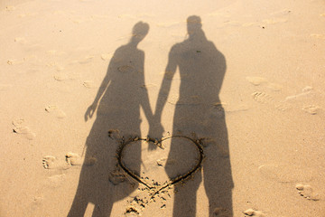 shadow of a couple of lovers on the beach with a heart in the sand