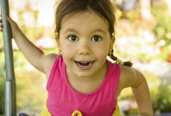 Outdoor portrait of expressive beautiful little girl smiling looking at the camera