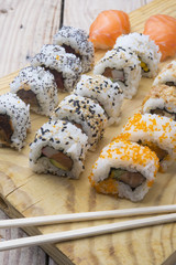 Different Sushi rolls,wasabi and ginger on a plate on wooden bac