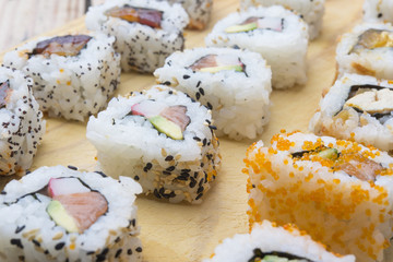 Different Sushi rolls,wasabi and ginger on a plate on wooden bac