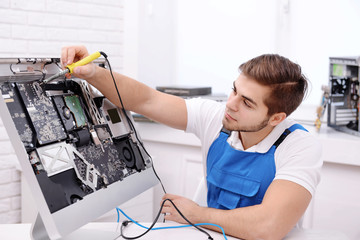 Young repairer working with soldering iron in service center