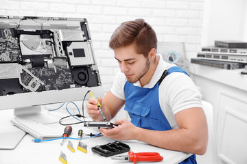 Young repairer working with soldering iron in service center