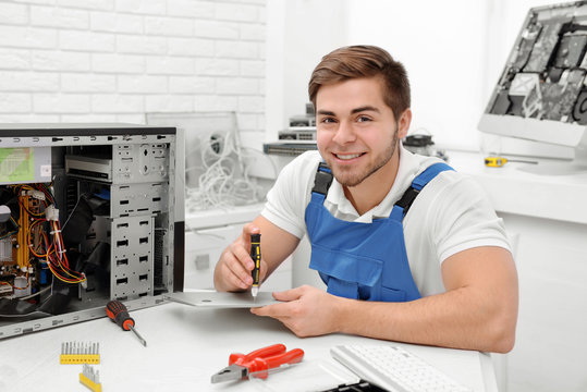 Young repairer working with screwdriver in service center